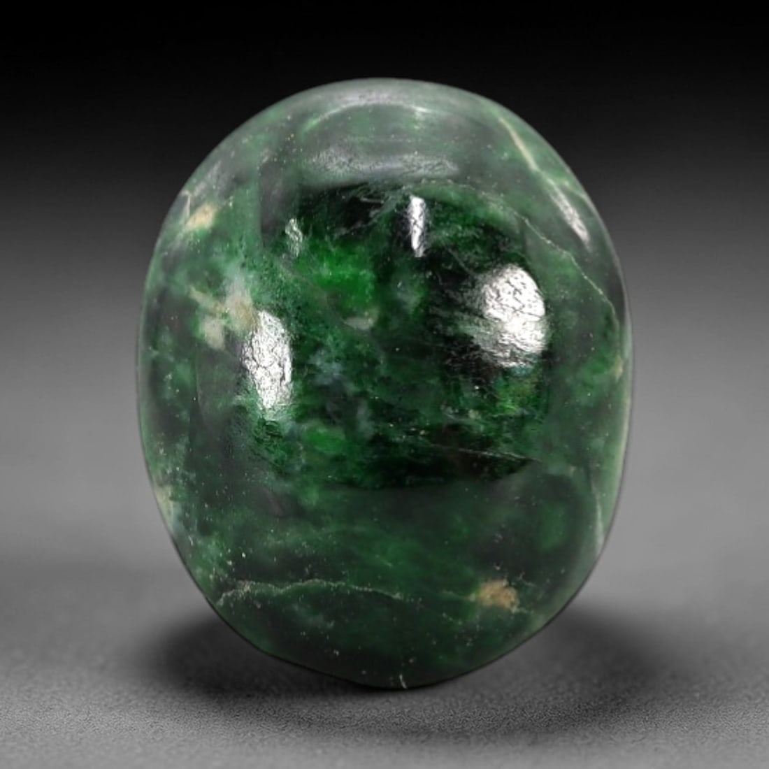 3.47 Carats Deep Green and Pale Matrix Maw Sit Sit Jade Cabochon - Natural Burmese Stone, 2AB: This maw sit sit jade cabochon is fashioned into an oval, domed form with a highly polished surface. The material exhibits a deep, saturated green matrix, interspersed with a pale, semi-translucent to