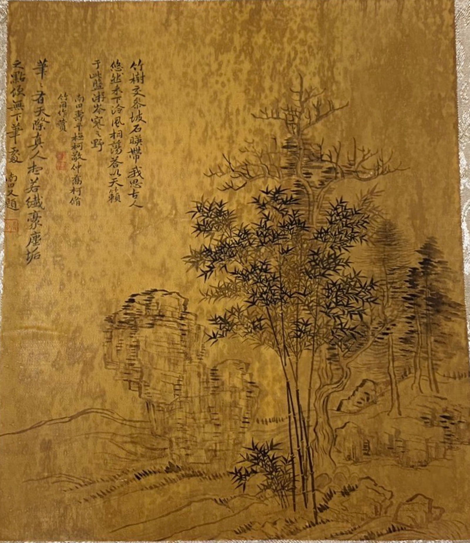 A Chinese Ink and Color Textile Print, Bamboo and Rock, 20th Century, 27FK: Printed on woven silk or hemp textile with a gold-toned ground, the composition depicts a classic literati scene of bamboo groves growing beside a rugged rock formation, with sparse trees and distant