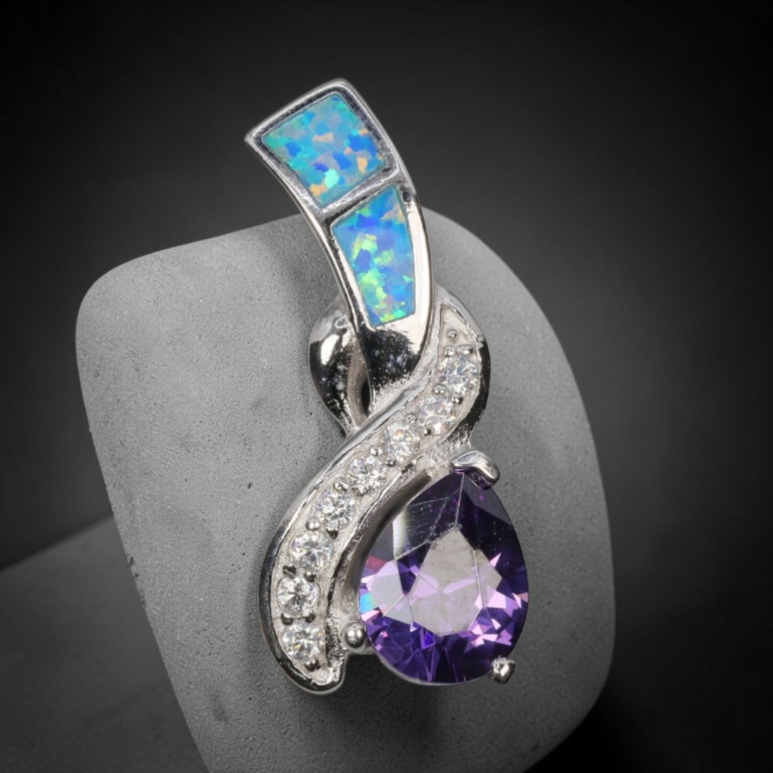 3.65g 925 Sterling Silver Swirl Pendant - Simulated Opal Amethyst, 34D: Crafted from stamped 925 sterling silver, this pendant features an elegant swirling openwork design. Two rectangular segments of simulated opal are inlaid along the upper curved silver band, exhibitin