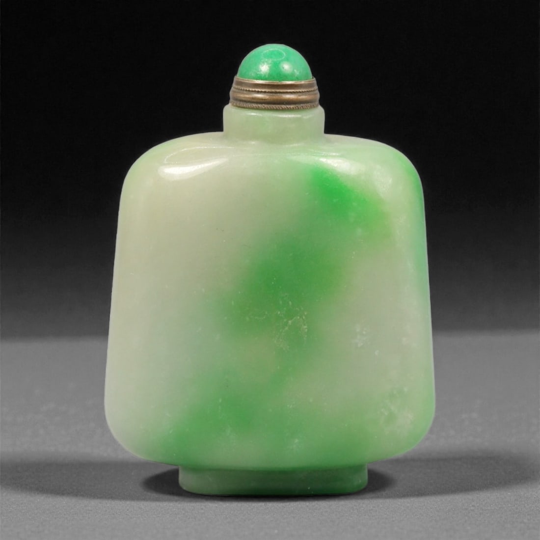A Chinese Jadeite Jade Snuff Bottle, 20th Century, 30YC: Carved from jadeite jade, the snuff bottle is of broad rectangular form with softly rounded corners and a slightly recessed foot, rising to a short cylindrical neck with a flat lip. The stone displays