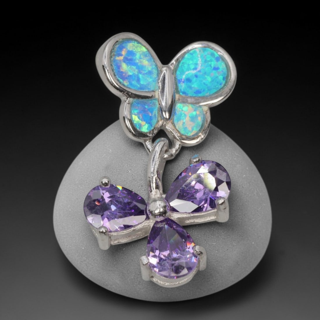 3.56g 925 Sterling Silver Butterfly Pendant - Simulated Opal Amethyst, 41D: Crafted from stamped 925 sterling silver, this pendant features a dual-butterfly design with polished openwork detailing. The upper butterfly is inlaid with four segments of simulated opal, displaying
