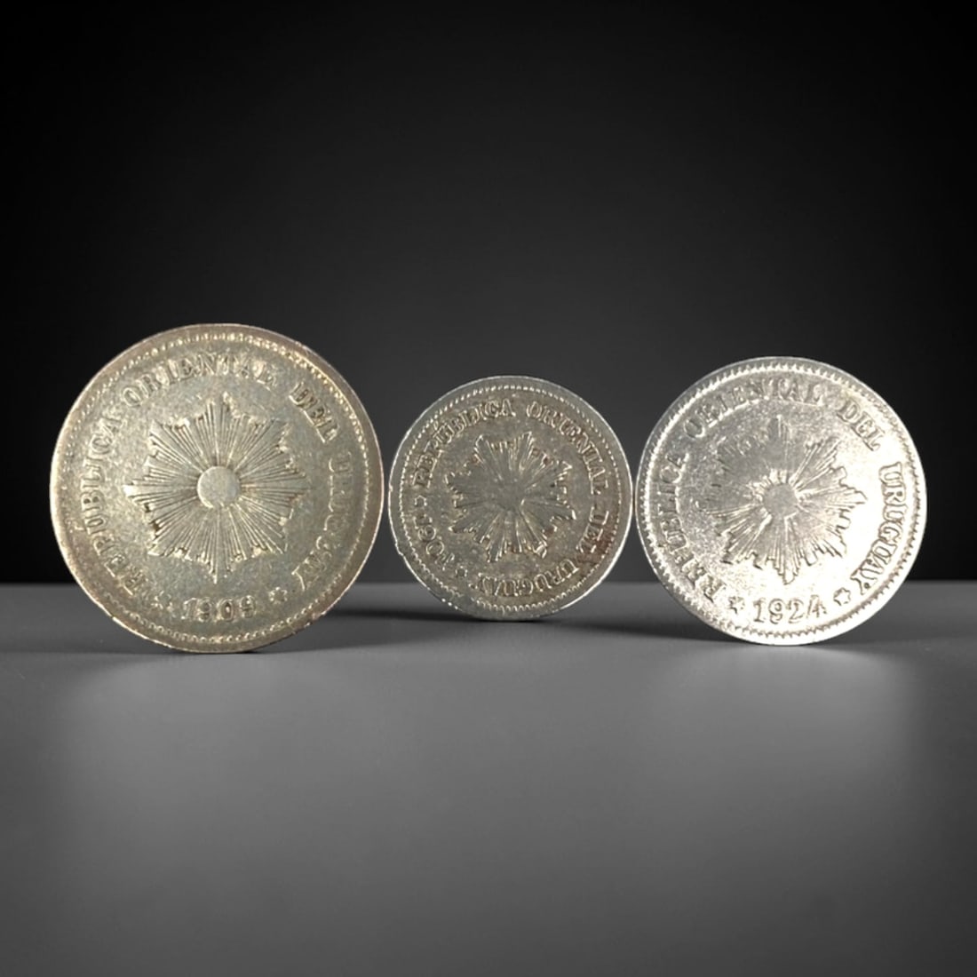 URUGUAY: National Identity & Sun of May - 3-Piece Coins Set, 1909-1924, 17-23mm, 15ZJ: This 3-Piece Coins Set of Uruguayan coins, minted between 1909 and 1924, encapsulates the nation's enduring national identity through the iconic Sun of May motif. Ranging from 17 to 23mm in diameter,