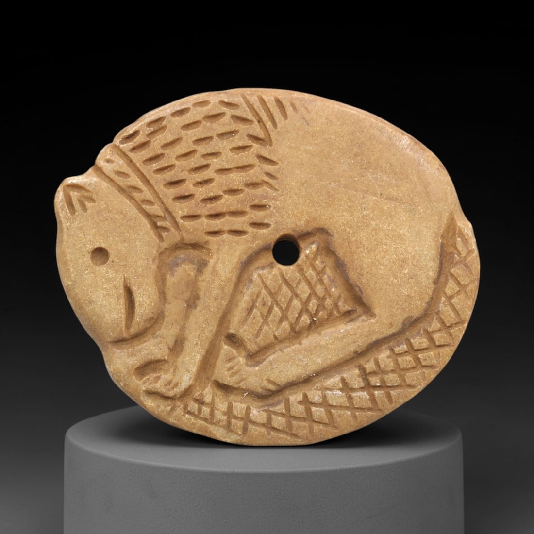 Ancient Stone Feline Amulet - Near Eastern Animal Pendant, 83ZP: Carved from warm tan stone, this oval amulet depicts a stylized feline in incised relief, with dotted patterns defining its fur and geometric motifs across its body. A central perforation confirms its