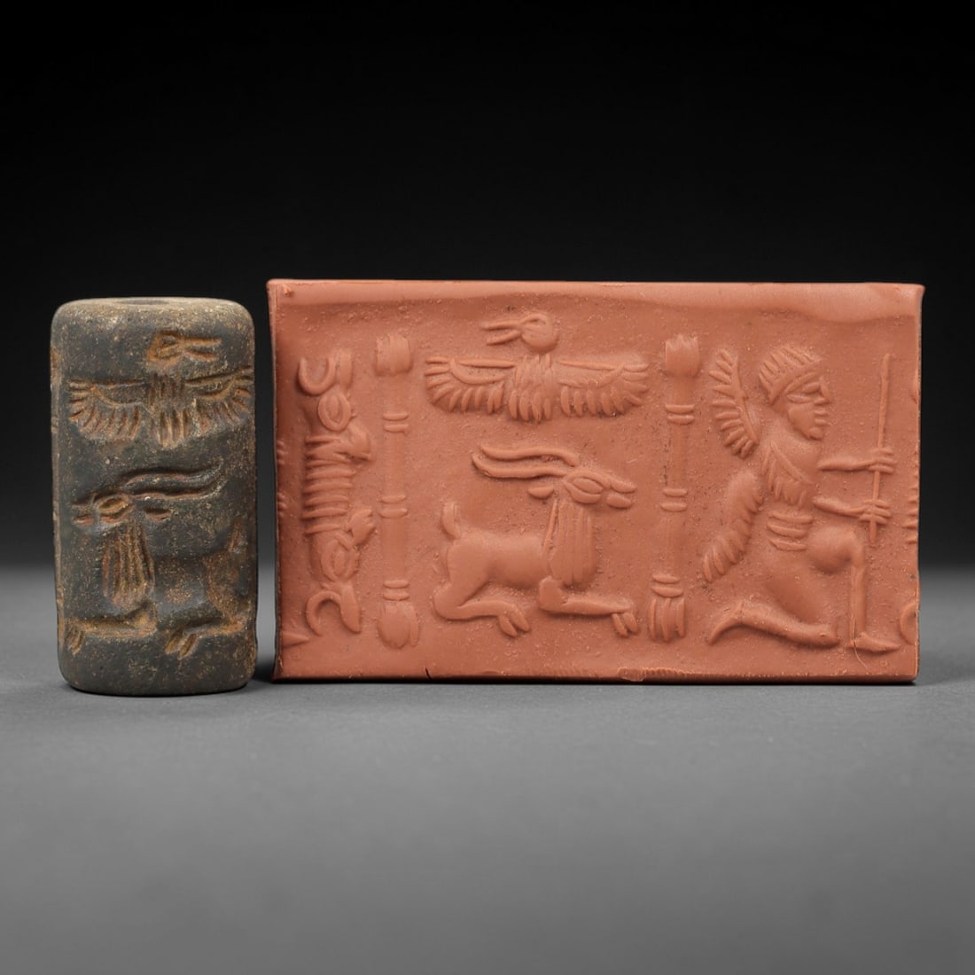 Ancient Steatite Cylinder Seal - Mesopotamian Winged Figure & Animal Scene, 73AN: Carved from dense steatite, this ancient Mesopotamian cylinder seal features a detailed linear relief composition of a kneeling winged humanoid figure alongside avian and caprine motifs, executed in t