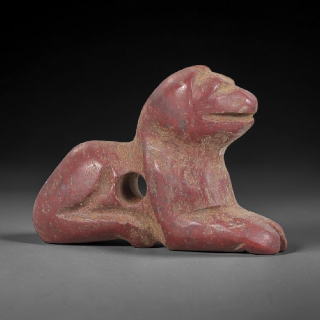 Ancient Stone Recumbent Feline - Egyptian Animal Figurine, 45AP: This artifact is carved from variegated red stone with a weathered, earthy patina and subtle mineral inclusions, exhibiting stylized feline features consistent with ancient Egyptian stoneworking techn