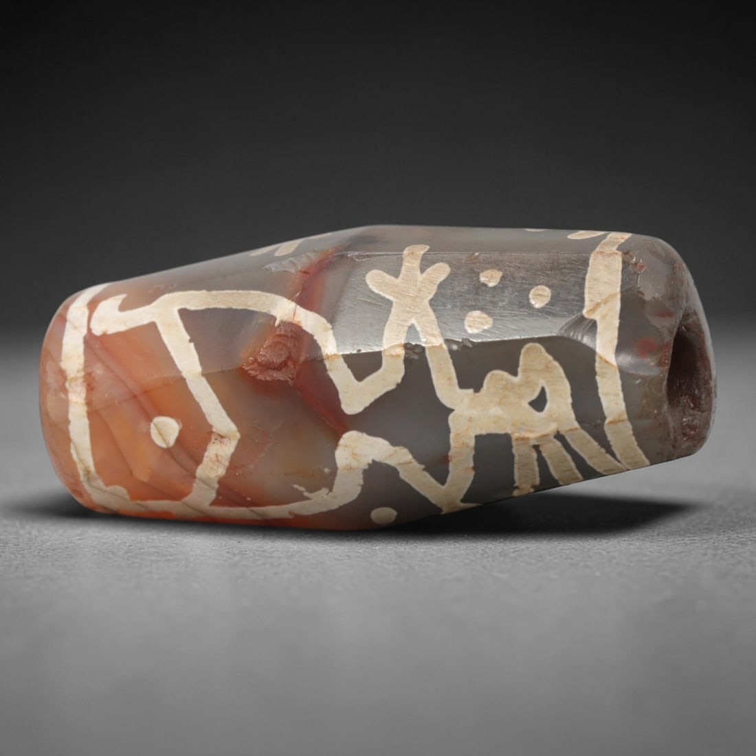 Ancient Agate Symbolic Motif Dzi Bead - Himalayan Amulet, 82XV: Crafted from translucent banded agate, this faceted bead features intricate etched white symbolic motifs including stylized human/animal forms and circular dots, executed in traditional Himalayan Dzi
