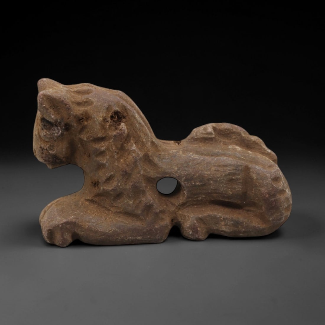 Ancient Limestone Feline Amulet - Near Eastern Figurine, 42ZQ: Carved from limestone, this small feline amulet exhibits a simplified, stylized form with incised detailing for facial features and body texture. The stone has a warm, earthy patina with minor surface
