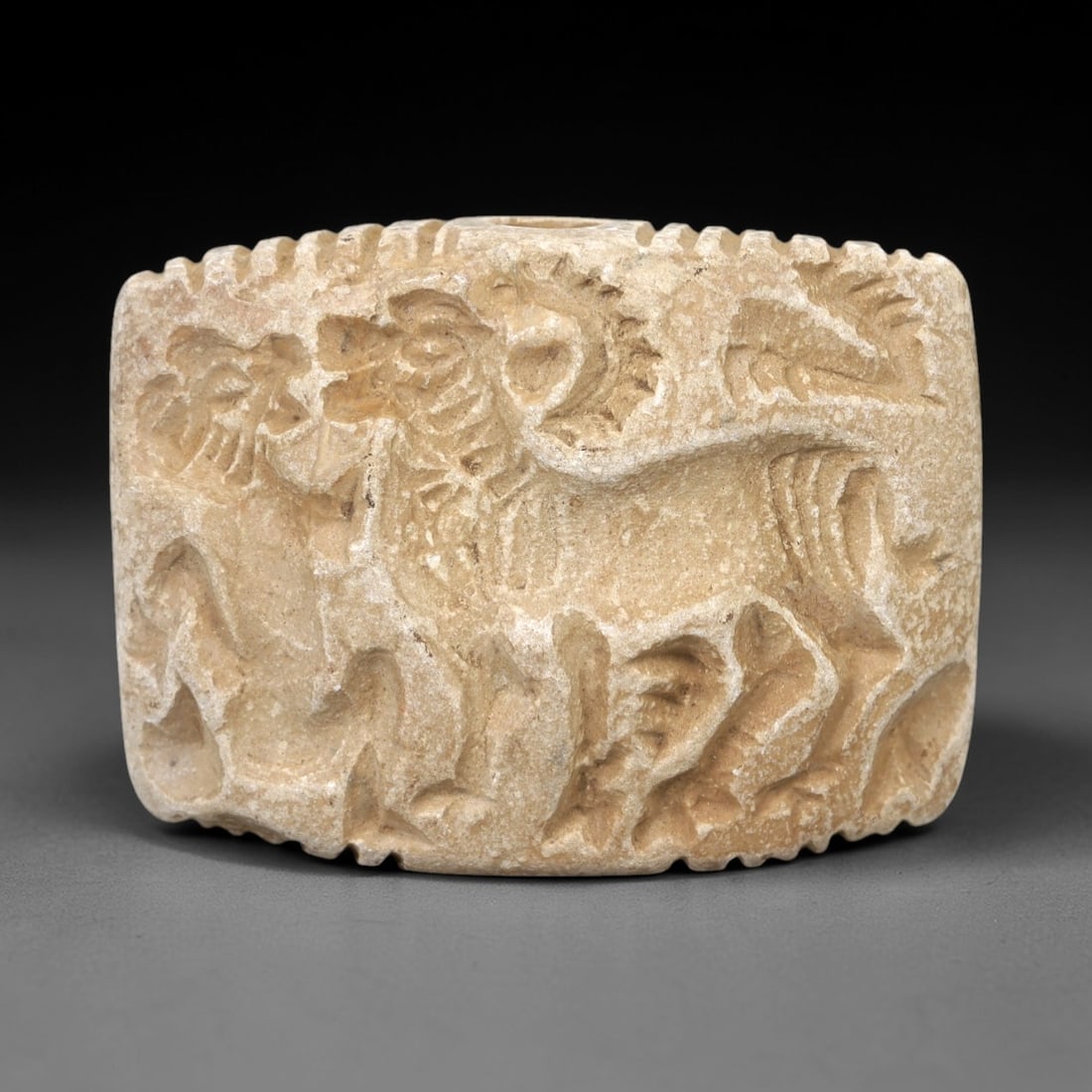 Ancient Limestone Double Convex Animal Relief Plaque - Near Eastern Ritual Relic, 52AN: Carved from limestone, this double convex plaque features intricate relief carvings of dynamic animal scenes-including a lion and a horned quadruped (likely a ibex or gazelle)-in combat or ritual inte