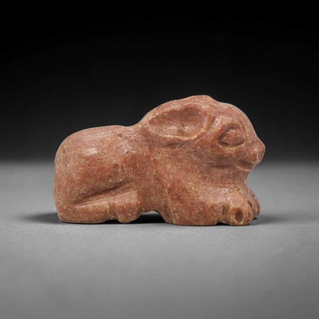 Ancient Stone Hare Amulet - Near Eastern Figurine, 5XT: This amulet is carved from a warm reddish stone with subtle earthy tonal variations and a matte, natural patina across its surface, crafted using a simplified yet expressive carving technique that cap