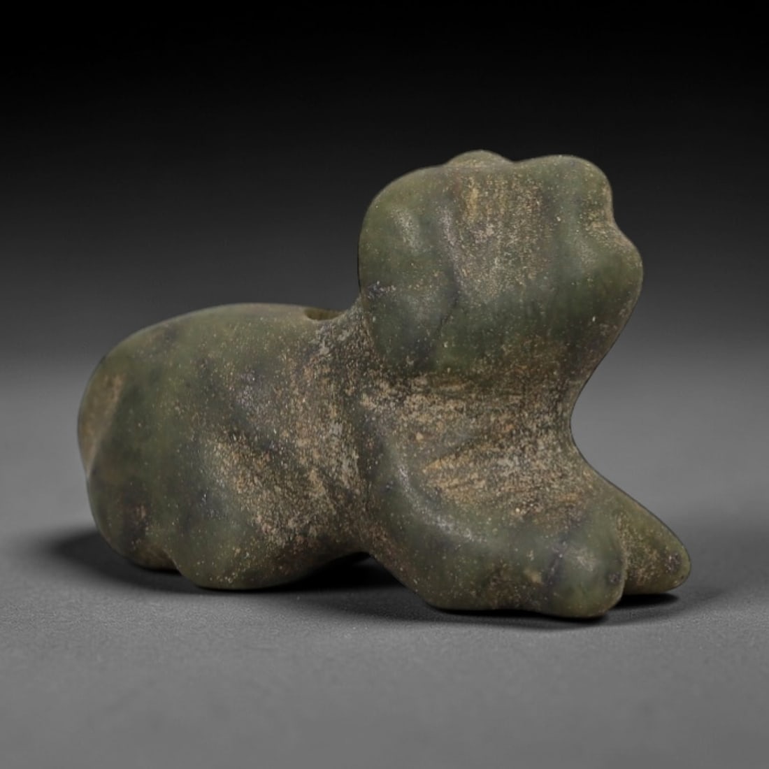 Ancient Green Stone Recumbent Zoomorphic Amulet - Near Eastern Talisman, 5AE: Carved from mottled green stone with natural mineral speckling and a weathered surface patina, this amulet depicts a stylized recumbent animal in a compact, rounded form. The creature is rendered with