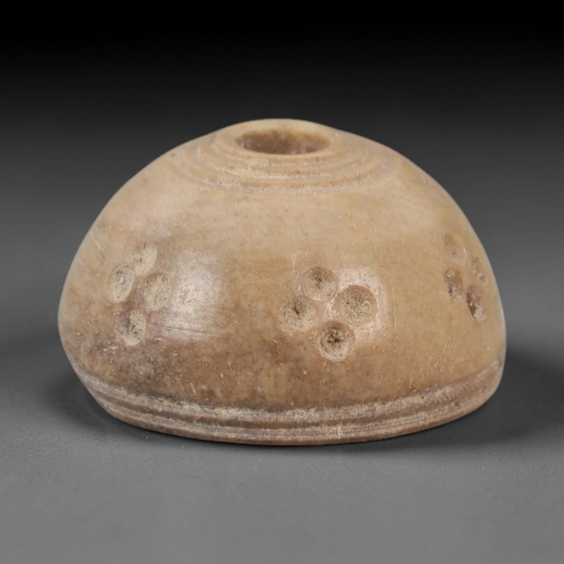 Ancient Near Eastern Bone Spindle Whorl - Four-Dot Motif, 94AH: Carved from ancient bone, this Near Eastern spindle whorl features a distinctive four-dot motif arranged around its central perforation, a geometric design with apotropaic significance in ancient Near