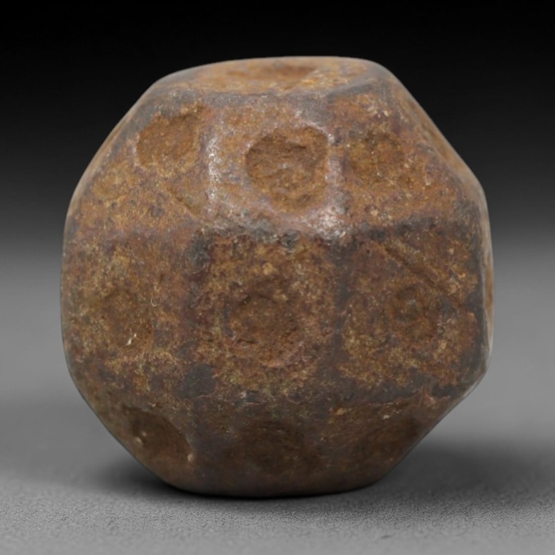Ancient Bronze Polyhedral - Near Eastern Relic, 40XV: Cast from bronze, this compact polyhedral relic features a faceted form with circular indentations across its surfaces, consistent with ancient Near Eastern or Medieval gaming or counting artifact tra