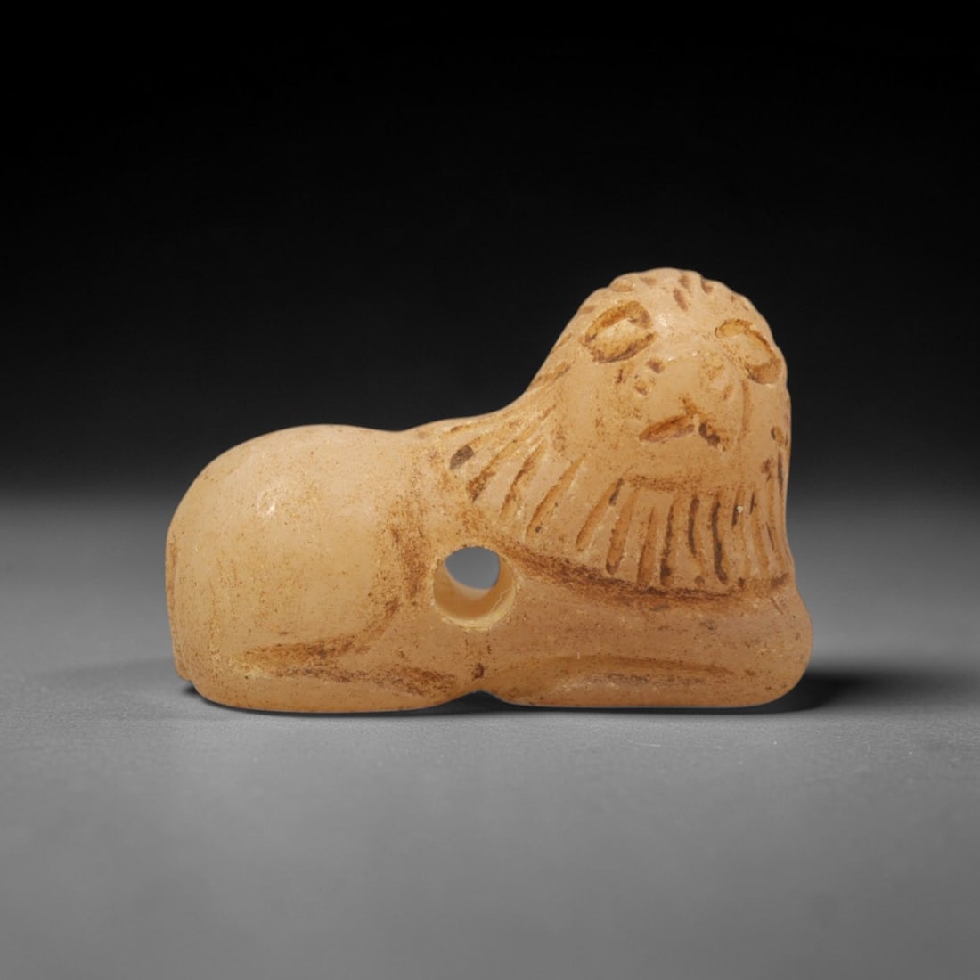 Ancient Chalcedony Feline Amulet - Near Eastern Figurine, 11XT: This amulet is carved from pale, translucent chalcedony with natural earthy inclusions and a warm, matte patina across its surface, executed in a refined yet stylized manner that emphasizes the recumb