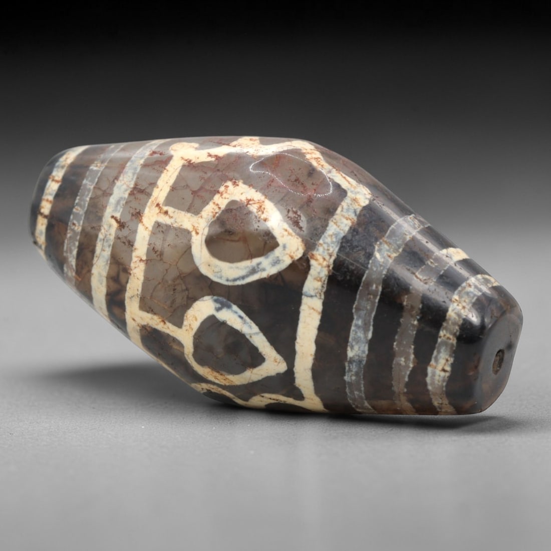 Ancient Agate 5-Eye Dzi Bead - Himalayan Amulet, 76XV: Crafted from dark translucent banded agate, this bead features five etched circular eye motifs, paired with wavy linear and horizontal band patterns, executed in the traditional Himalayan Dzi bead tec