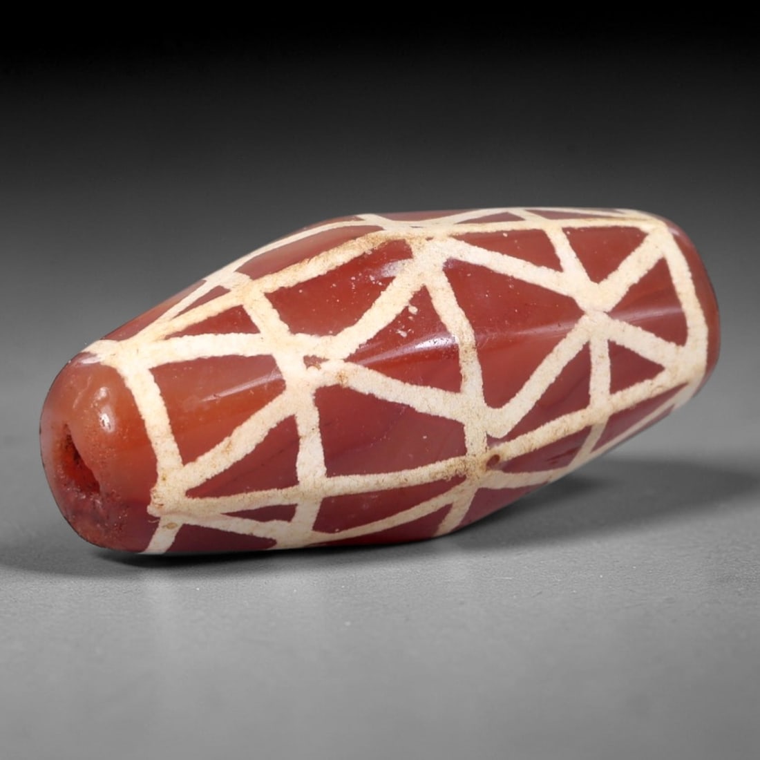 Ancient Carnelian Etched Bead - Himalayan Lattice Amulet, 96AR: This ancient elongated bead is crafted from polished carnelian, featuring a rich reddish-brown base with crisp white etched lattice geometric motifs across its multi-faceted surface. The bead retains