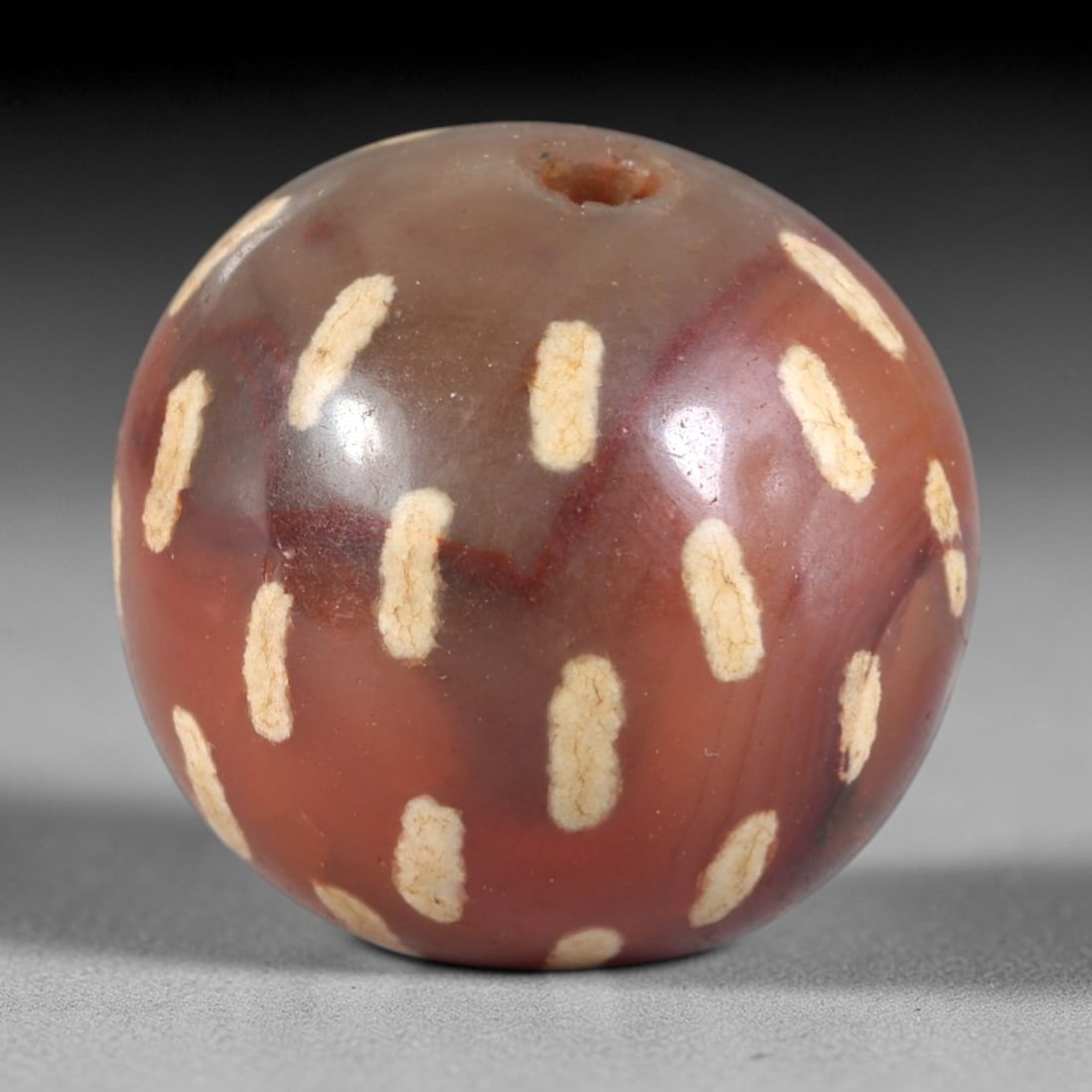 Ancient Carnelian Etched Bead - Himalayan Amulet, 93AR: This ancient spherical bead is crafted from polished carnelian, featuring a rich reddish-brown base with evenly spaced white etched oval motifs across its surface. The bead retains a central drilled s