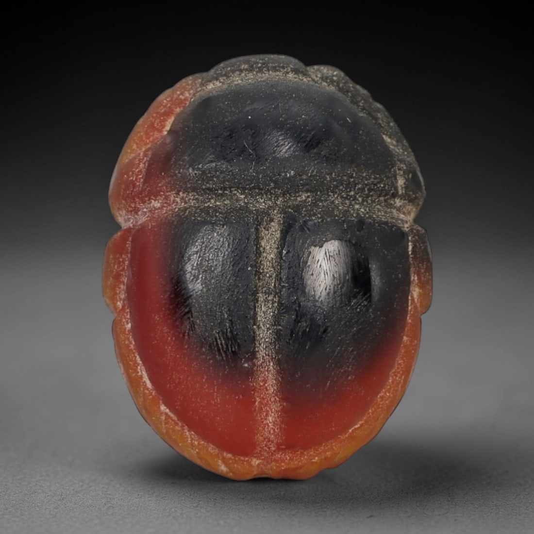 Ancient Banded Agate Scarab Amulet - Egyptian Figurine, 20AJ: Carved from striking banded agate with a dramatic black-to-reddish-orange gradient, this amulet is formed as a stylized scarab beetle with subtle linear detailing to define segmented wing cases and bo
