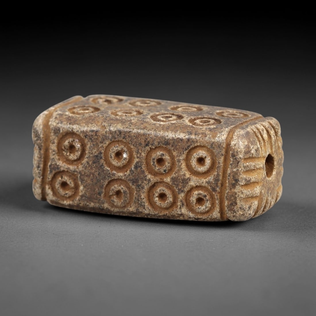 Ancient Steatite Amulet - Near Eastern Concentric Circles, 39AK: Crafted from steatite, this elongated rectangular amulet features incised concentric circle motifs arranged in a 2x4 grid across its primary face, with decorative linear carvings framing the suspensio