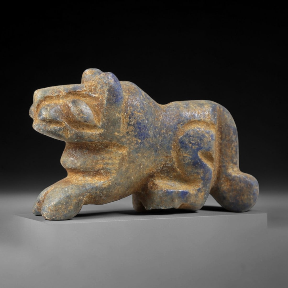 Ancient Lapis Lazuli Feline - Near Eastern Amulet Figurine, 35AS: Carved from lapis lazuli, this amulet depicts a striding feline form with stylized, geometric features. The head is forward-facing, with prominent incised eyes, a broad snout, and small rounded ears,