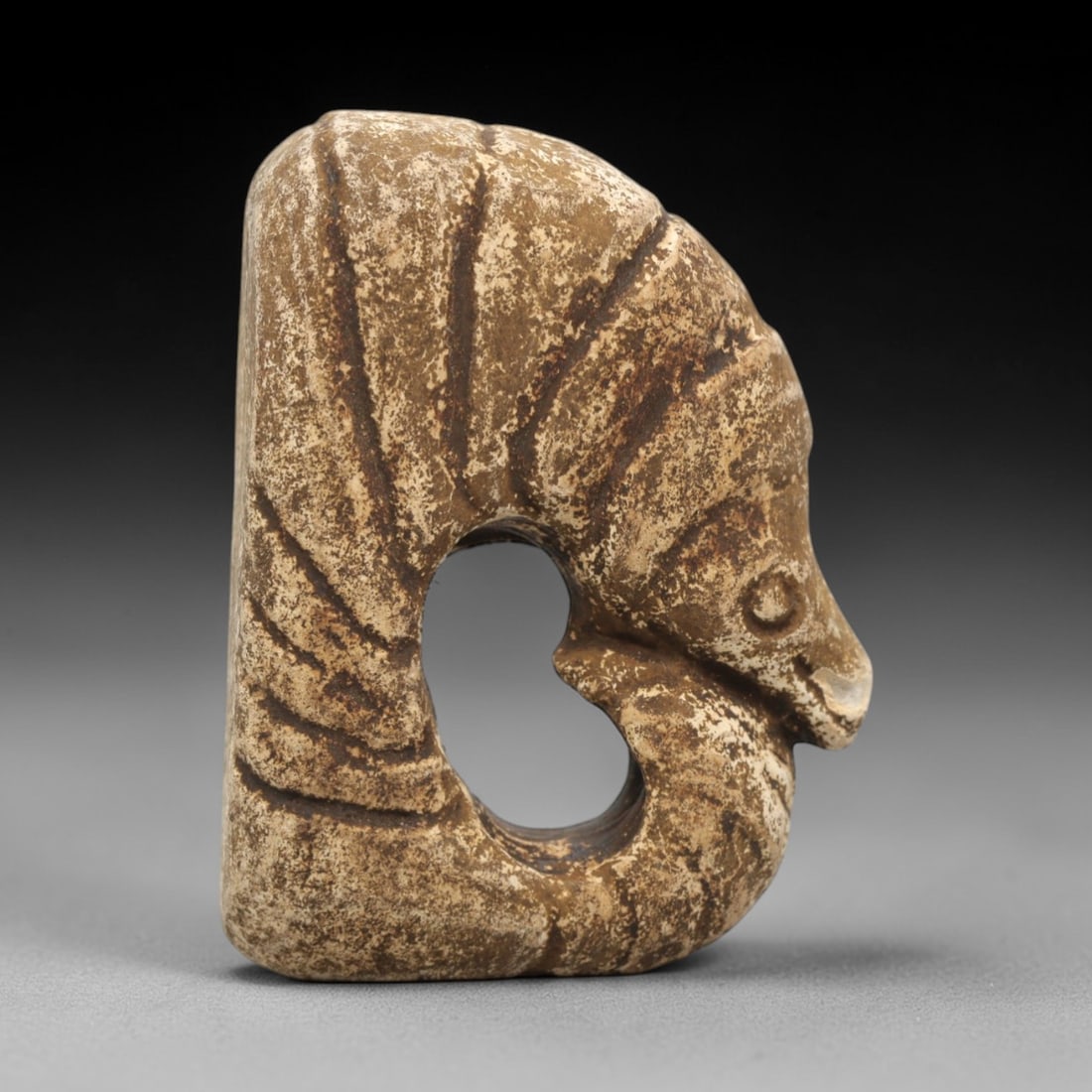 Ancient Stone Zoomorphic Amulet - Near Eastern Carving, 75ZV: This artifact is a carved stone zoomorphic amulet, crafted from a granular, earth-toned stone consistent with ancient Near Eastern lithic traditions. The relief carving depicts a stylized creature wit