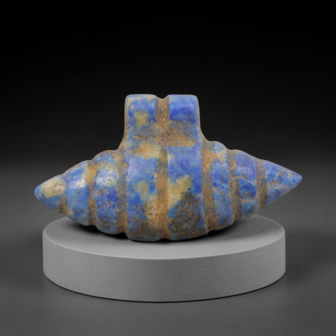 Ancient Lapis Lazuli Shell Form Amulet - Egyptian Ritual Pendant, 24ZT: Carved from lapis lazuli, this amulet features a symmetrical double-pointed shell-like form with a raised central lug pierced for suspension, its body incised with horizontal bands that define its seg