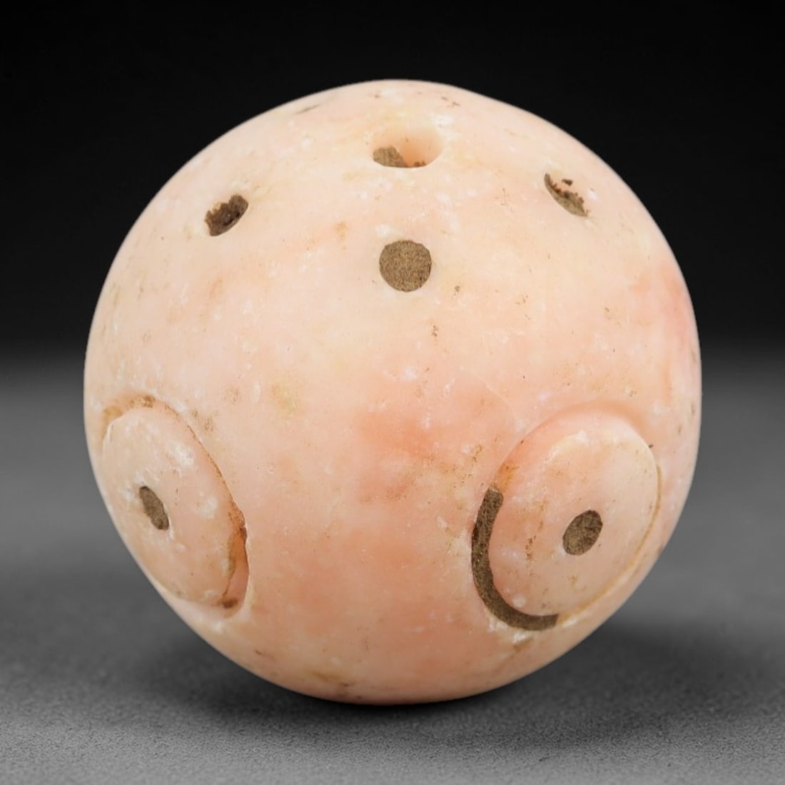 Ancient Calcite Spherical Bead - Near Eastern Amulet, 33AK: Carved from pale pink calcite, this spherical bead features multiple evenly spaced perforations and raised circular motifs, each incised with a central dot, characteristic of Near Eastern Bronze or Ir