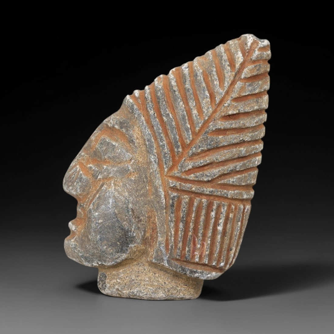 Ancient Stone Portrait Amulet - Near Eastern Head Figurine, 58AM: This artifact is carved from a granular, weathered stone with a warm, earthy patina consistent with ancient Near Eastern burial contexts. The form depicts a stylized human head in profile, featuring a