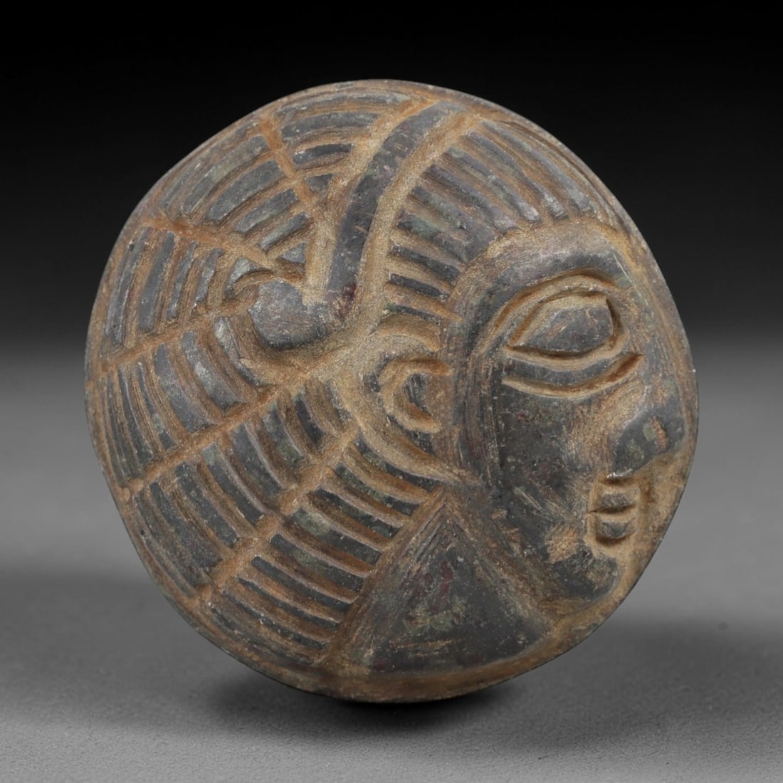 Ancient Basalt Bust Plaque - Egyptian Idol Head, 46AH: Carved from basalt, this ancient Egyptian bust plaque features a stylized human facial form with detailed eye sockets, subtle facial features, and a textured surface typical of Egyptian artistic tradi