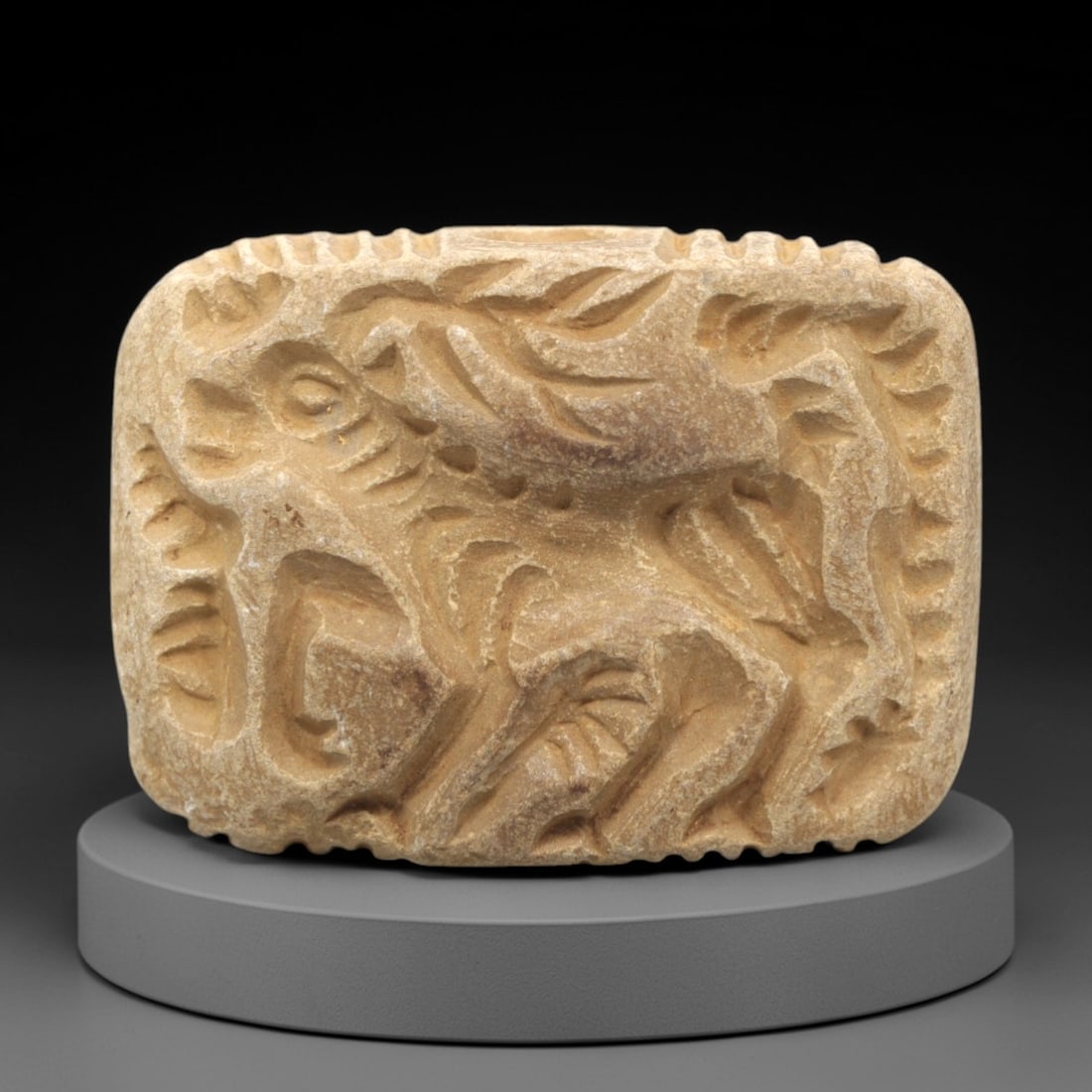 Ancient Stone Double Convex Amulet Bead - Near Eastern Animal Figurine, 9ZS: This artifact is a carved stone double convex amulet bead, featuring a dynamic animal motif executed in the stylized glyptic tradition of the ancient Near East. The bead's form is defined by raised co