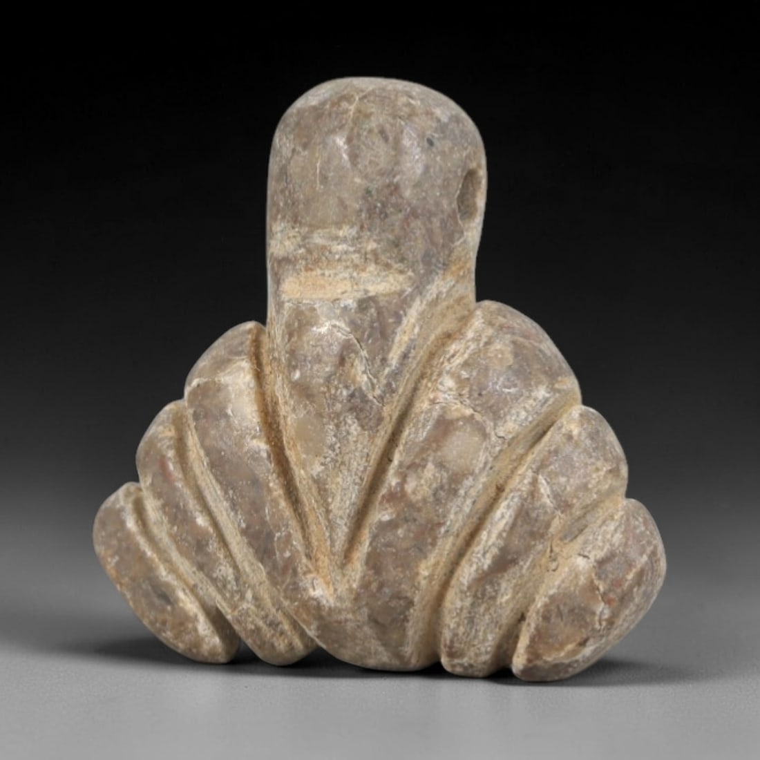 Ancient Stone Amulet - Near Eastern Ritual Figurine, 65AP: This artifact is carved from light gray stone with a weathered, earthy patina and visible surface fissures, exhibiting symmetrical, ribbed detailing consistent with ancient Near Eastern stoneworking t