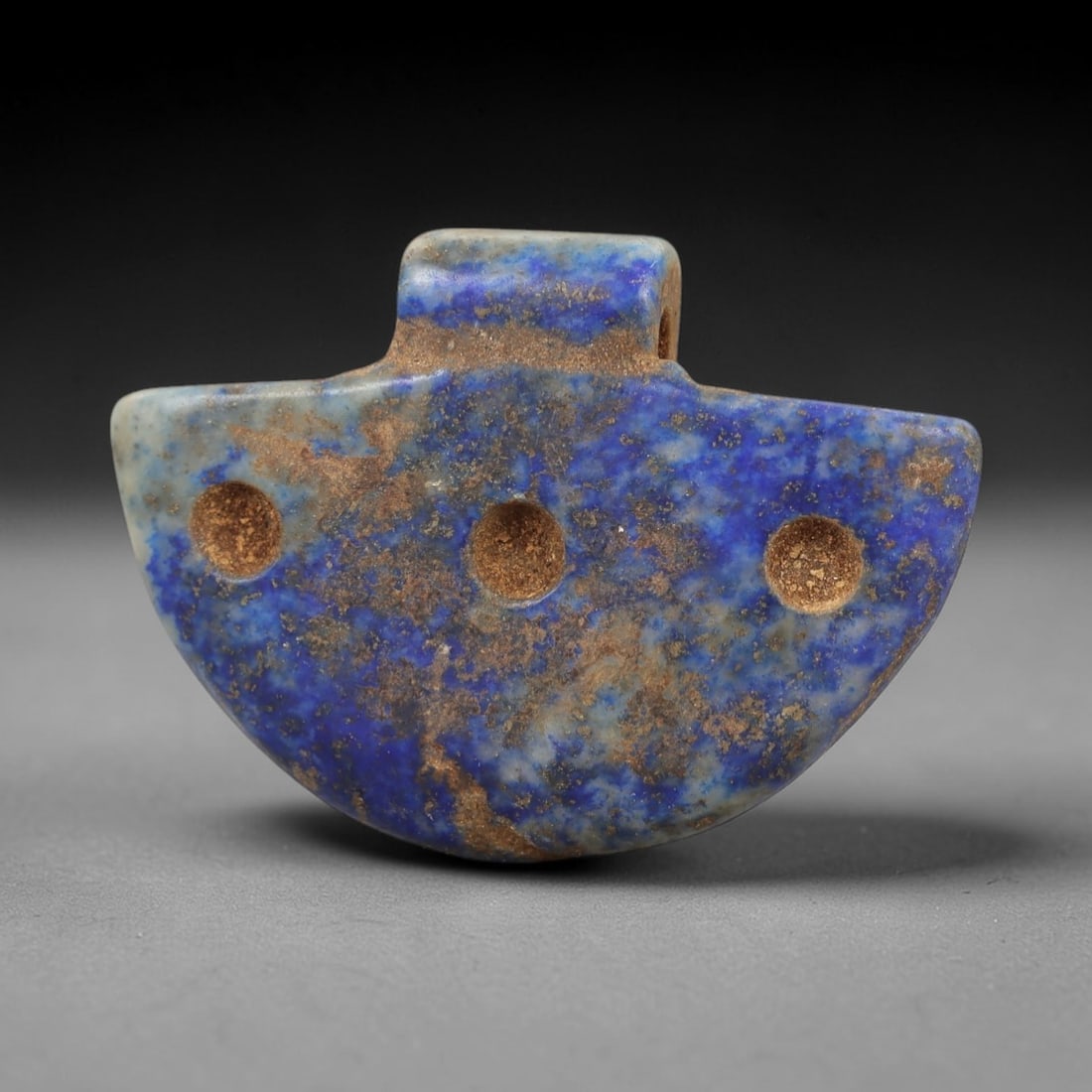 Ancient Lapis Lazuli Amulet - Egyptian Ritual Pendant, 15AP: Carved from lapis lazuli, this amulet features a semicircular, fan-like form with a raised rectangular lug at the top pierced for suspension, its flat surface marked by three evenly spaced recessed ci
