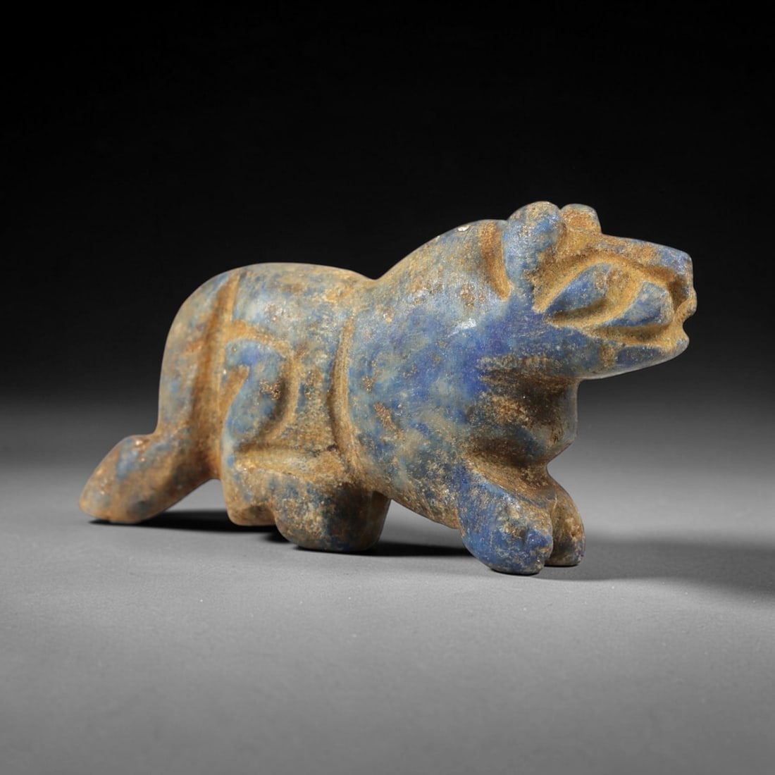 Ancient Lapis Lazuli Feline - Near Eastern Amulet Figurine, 33AS: Carved from lapis lazuli, this amulet depicts a striding feline, likely a lion or leopard, with stylized features and a powerful, elongated body. The head is forward-facing with distinct, incised eyes