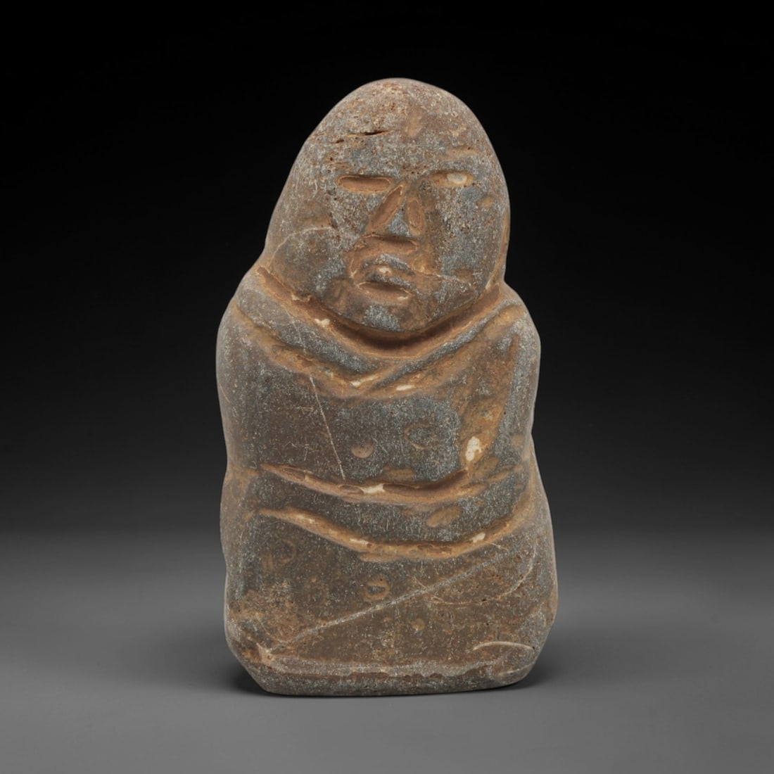 Ancient Stone Monk - Japanese Edo Period Figurine, 52FX: Carved from a coarse, mottled stone, this Edo period figure depicts a monk in a standing posture, wrapped in layered robes defined by incised linear details. The face is stylized with recessed eye soc