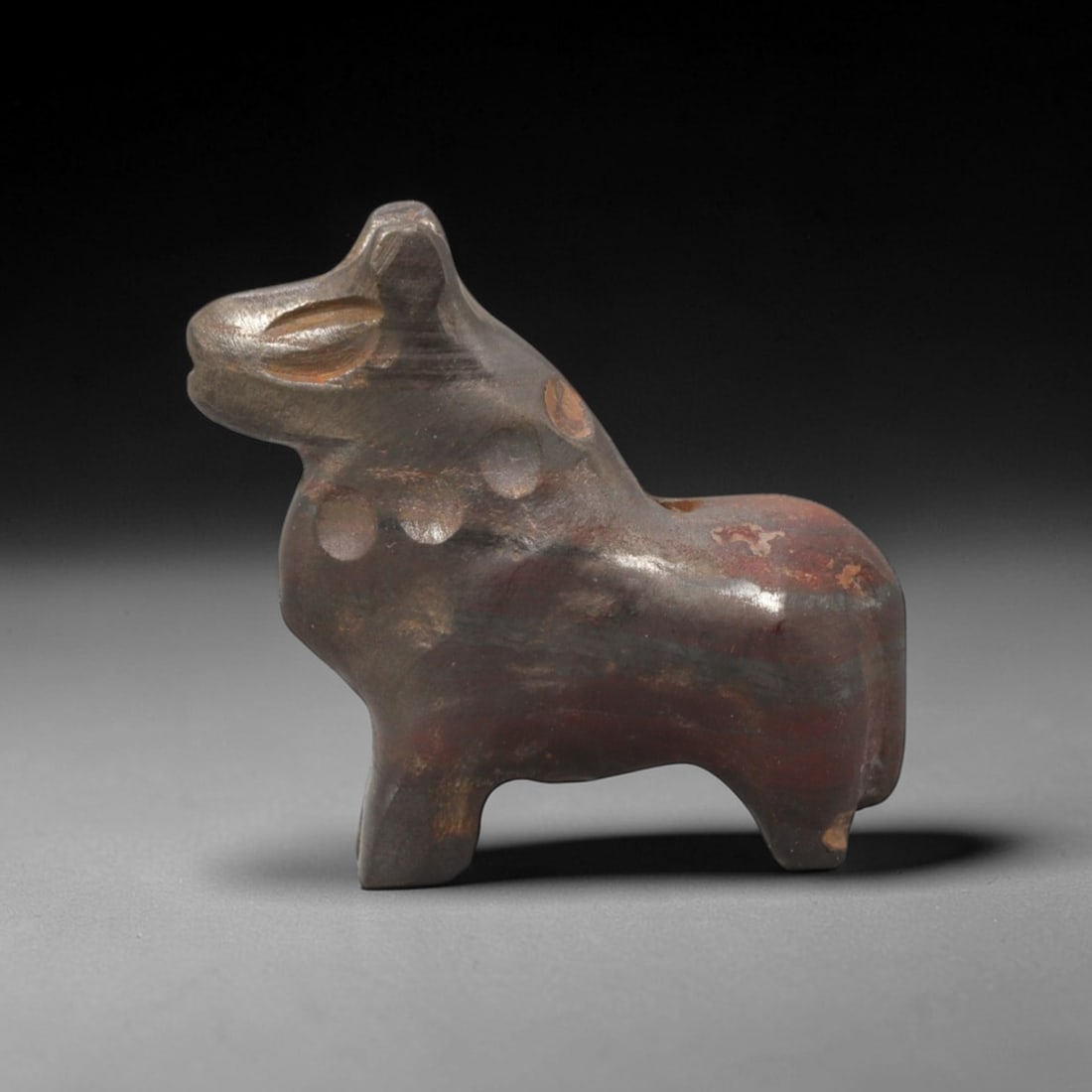 Ancient Hematite Feline Amulet - Near Eastern Figurine, 95XV: This amulet is carved from dense, dark hematite with subtle banded iron mineralization and a rich, matte patina across its surface, executed in a stylized, upright form that emphasizes the feline's re