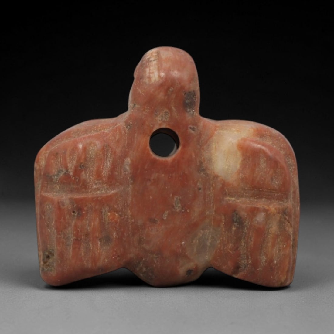 Ancient Stone Vulture - Near Eastern Amulet Figurine, 48ZV: This amulet is carved from variegated reddish stone, shaped into a stylized vulture with outstretched wings, a motif linked to protection and divine association in ancient Near Eastern iconography. A