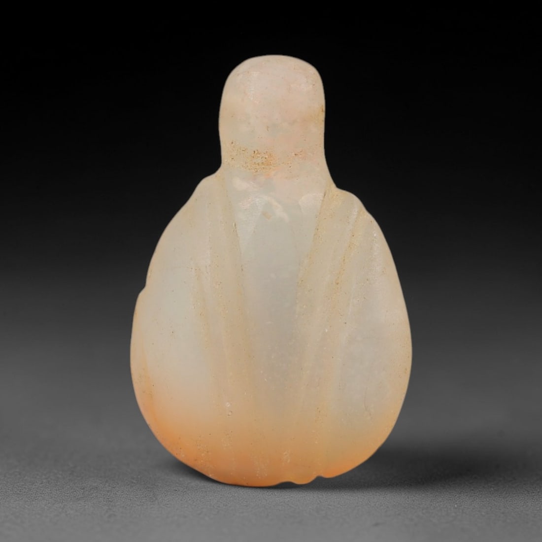 Ancient Chalcedony Heart Amulet - Egyptian Figurine, 37AJ: Carved from pale translucent chalcedony with warm orange undertones, this amulet is formed as a stylized heart with a simplified rounded head and incised linear detailing across the body to define str