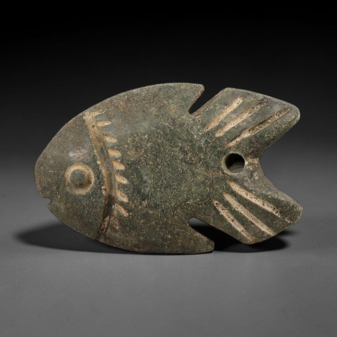 Ancient Egyptian Stone Fish Amulet - Nile Carp Carving, 61AE: Carved from stone, this ancient Egyptian fish amulet depicts a Nile carp, a species symbolizing fertility and rebirth in ancient Egyptian religious beliefs. The stylized carving features incised detai