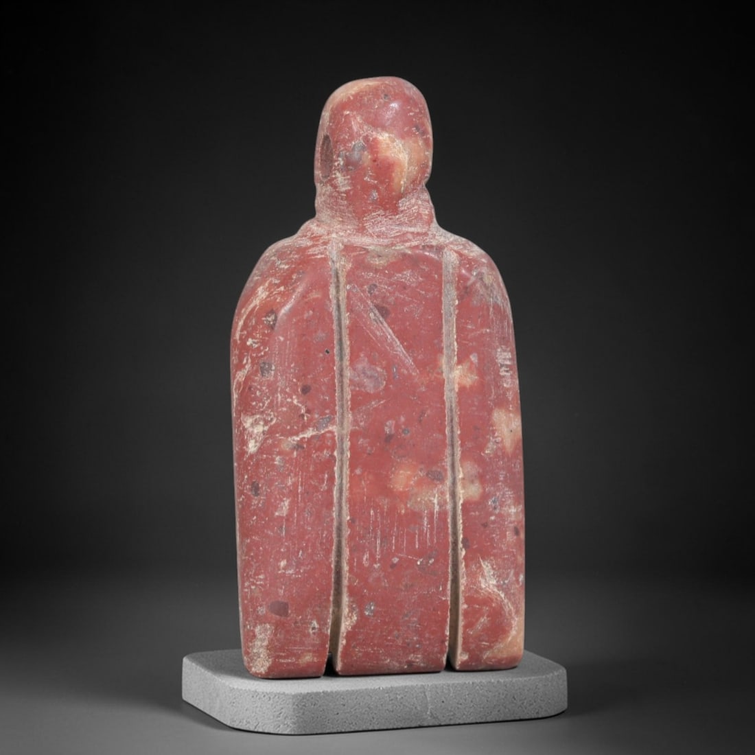 Ancient Stone Anthropomorphic Amulet - Near Eastern Figurine, 34AP: Carved from a rich, reddish stone with natural mineral inclusions and lighter weathered patina, this amulet depicts a stylized anthropomorphic form with a simplified, rounded head and broad, verticall