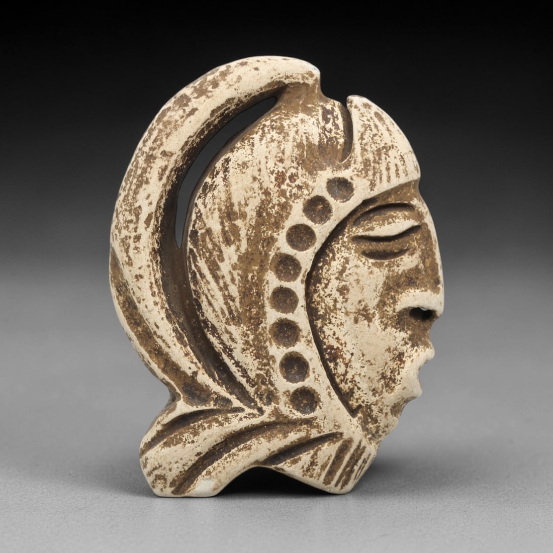 Ancient Stone Anthropomorphic Head - Near Eastern Amulet, 81ZV: This artifact is a carved stone anthropomorphic head amulet, crafted from a light-toned, granular stone consistent with ancient Near Eastern lithic traditions. The relief carving depicts a stylized pr