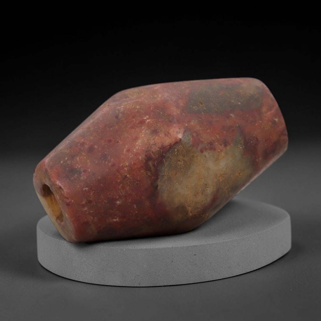 Ancient Stone Tubular Amulet - Near Eastern Pendant, 34AG: This amulet is carved from a mottled red and beige stone with a weathered, earthy patina and natural mineral veining. The form is a tapered tubular bead, with rounded ends and a large central drilled