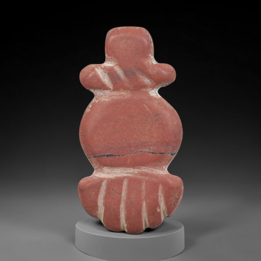 Ancient Stone Amulet - Near Eastern Ritual Figurine, 92AP: This artifact is carved from variegated red stone with a weathered patina and subtle mineral veining, exhibiting incised linear detailing consistent with ancient Near Eastern stoneworking techniques.