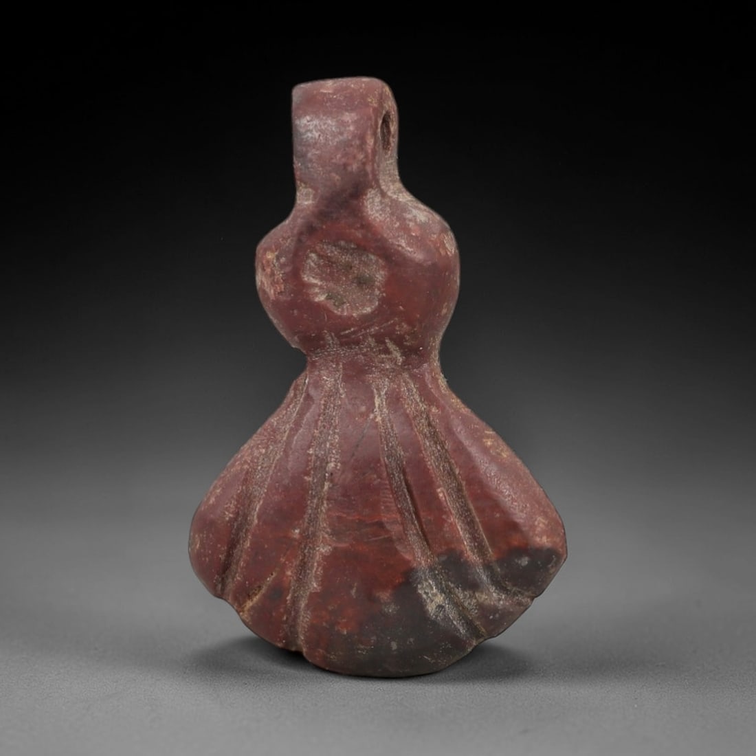 Ancient Red Stone Pendant - Egyptian Style Figurine, 57AG: Carved from red stone, this ancient Egyptian-style pendant features a compact, stylized form with defined facial and body details and a suspension hole at the top, indicating its use as a wearable amu