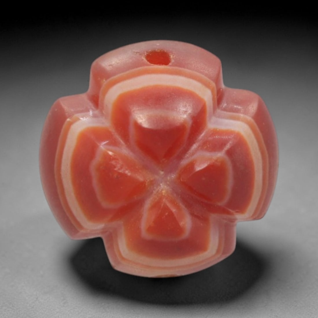 Antique Agate Four-Petaled Flower Bead - Central Asian Carved Gemstone, 13ZW: Carved from banded agate with a rich coral-red base and creamy white concentric banding, this bead features a symmetrical four-petaled floral form with faceted, raised petals that create a layered, ge