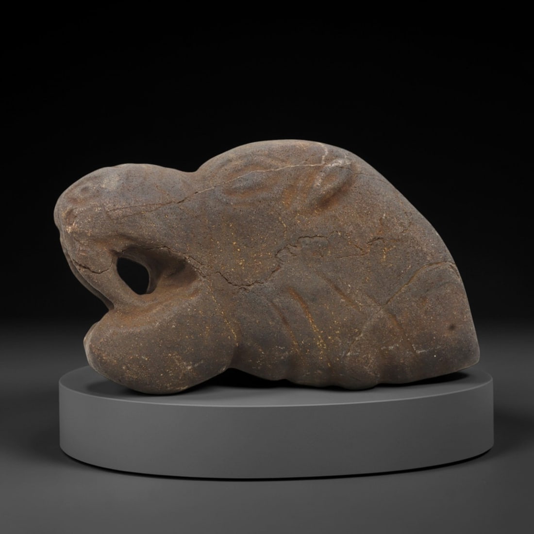 Ancient Stone Feline Head - Tribal Animal Figurine, 33FX: Carved from a dense, earthy-brown stone with a granular matrix, this artifact depicts a stylized feline head with a prominent open mouth, recessed eye sockets, and incised linear details defining the