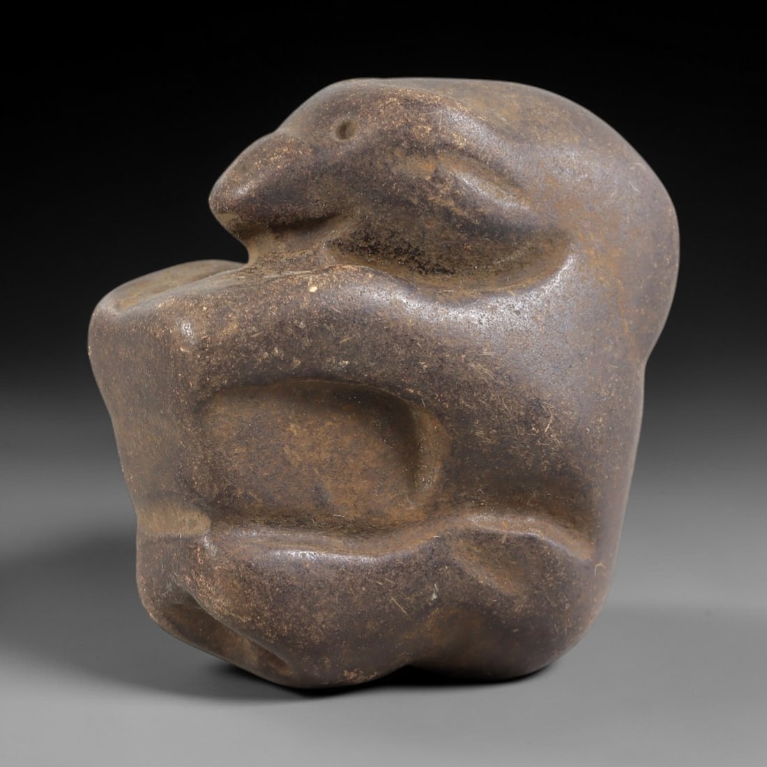 Ancient Stone Zoomorphic Effigy - Near Eastern Figurine, 5FY: Carved from a dense, smooth stone, this effigy depicts a stylized crouching animal-likely a rodent or small mammal-in a compact, rounded form. Relief details define the snout, circular eye socket, and