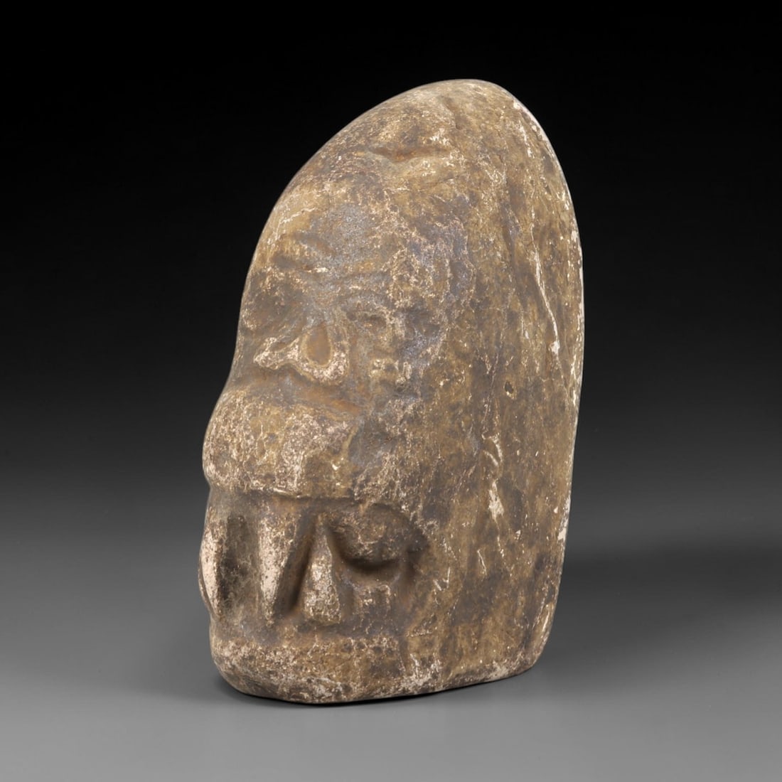Ancient Stone Zoomorphic Head Effigy - Near Eastern Figurine, 94FX: Carved from a dense, weathered stone, this effigy depicts a stylized zoomorphic head-likely a canine or feline-in profile, with relief carvings defining the snout, nasal perforations, and facial conto