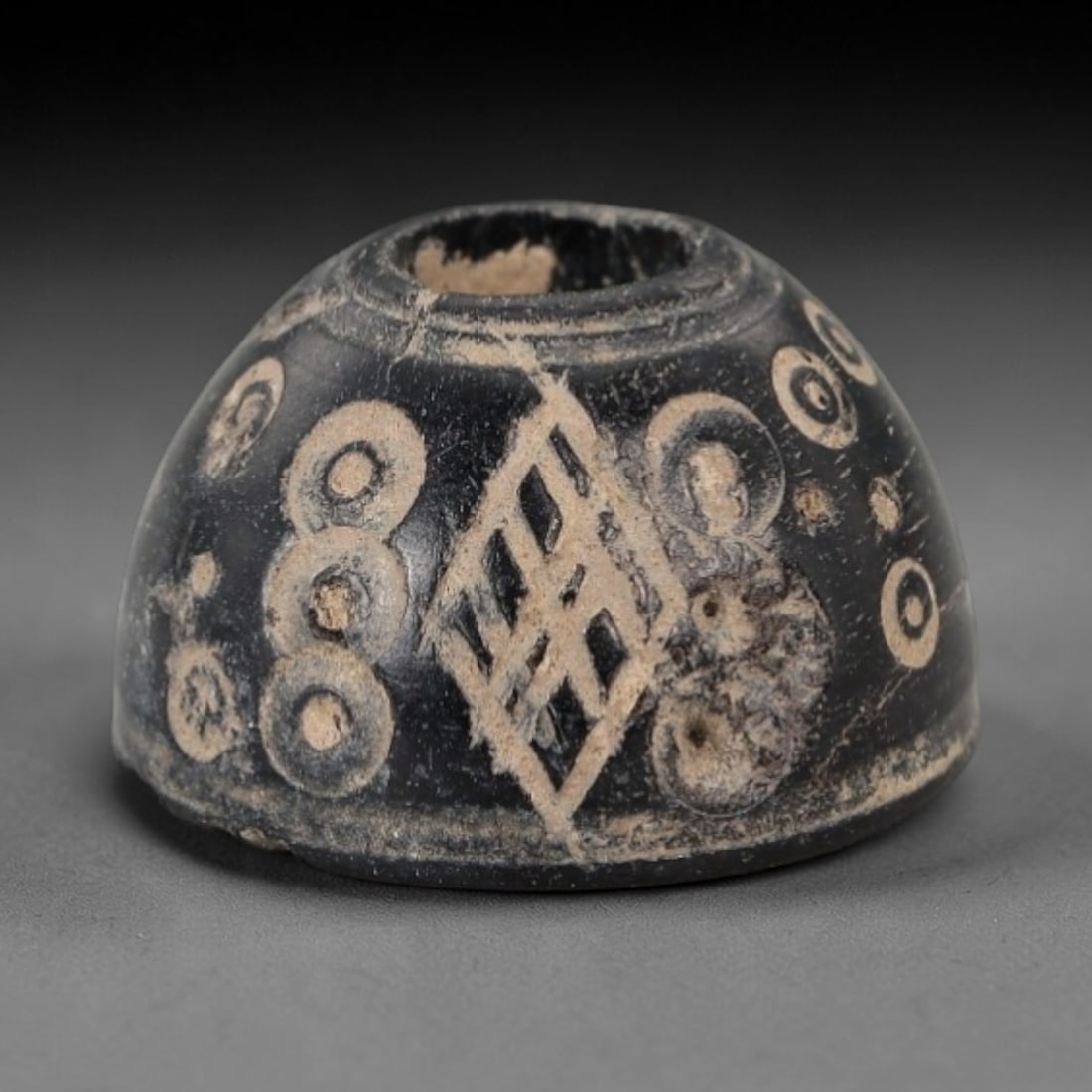 Ancient Bone Spindle Whorl - Near Eastern Cross-and-Dot Motif, 77XR: This ancient Near Eastern spindle whorl is crafted from bone, featuring incised cross-and-dot geometric patterns radiating from the central perforation. The compact, rounded form is a traditional text
