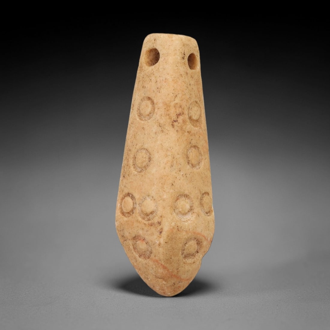 Ancient Egyptian Stone Amulet - Geometric Carved Pendant, 31AE: Carved from light-toned stone, this ancient Egyptian amulet features an elongated, tapering form with a series of evenly spaced circular incisions along its length, a motif typical of Egyptian protect