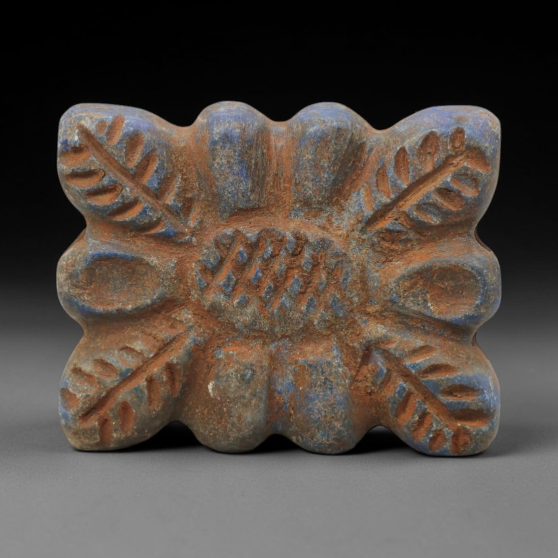 Ancient Lapis Lazuli Amulet - Near Eastern Floral Motif, 8ZQ: Carved from deep blue lapis lazuli, this amulet features a stylized floral and foliate motif with incised linear detailing. The stone exhibits natural pyrite inclusions and a subtle, aged patina consi