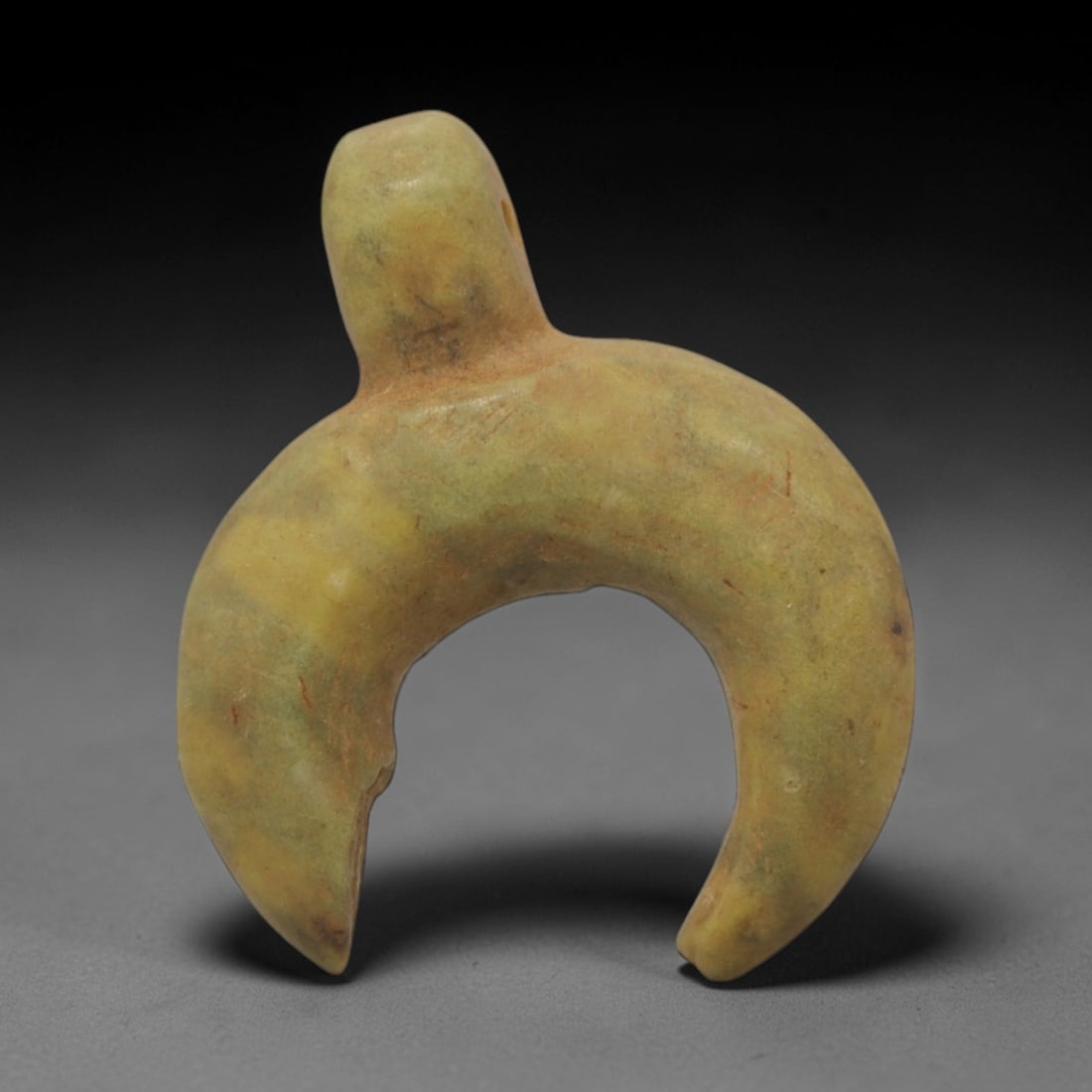 Ancient Stone Crescent Amulet - Near Eastern Pendant, 25XQ: Carved from a pale yellowish-green stone with subtle earthy patination, this amulet takes a distinct crescent (lunar) form with a rounded suspension loop integrated at the apex and a small split at on